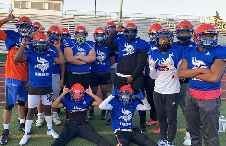 Viking football team posing together on the field in blue jerseys and orange helmets